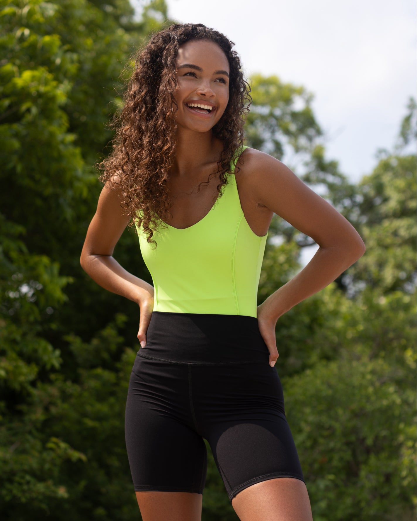 Model wearing Riviera Bodysuit in Lime Green color with black bike short